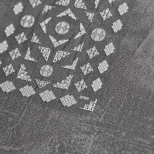 Macro shot of 3D embossed nail art stickers with white traditional cloud and knot patterns