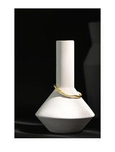 Detail of minimalist wavy gold cuff bracelet on a white geometric vase with high contrast