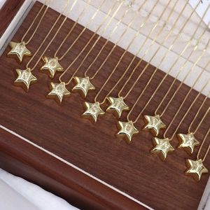 Detail view of 12 gold star-shaped necklaces with zircon-inlaid letters on wood display