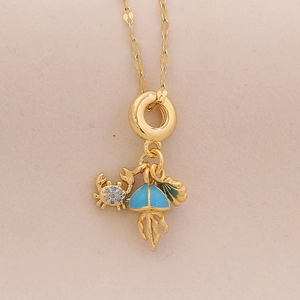 Gold ocean necklace featuring crab, shell, and jellyfish pendants with blue crystals