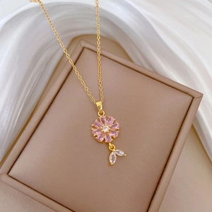 Macro detail of gold flower necklace with pink gemstones and zircon leaf on silk
