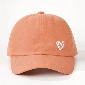 Detail of coral cotton baseball cap showing white heart embroidery and twill texture