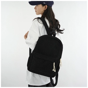 Side view of a large black corduroy backpack worn by a model against a clean background