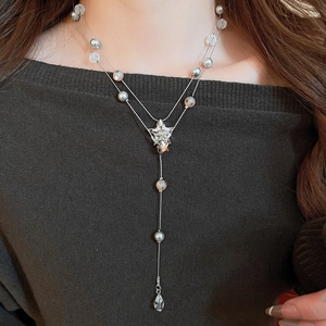 Detailed view of silver Y-shaped double necklace with star and teardrop pendants