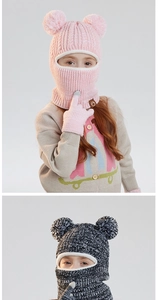 Detail of children's knit balaclava featuring fluffy pom-poms and warm fleece lining