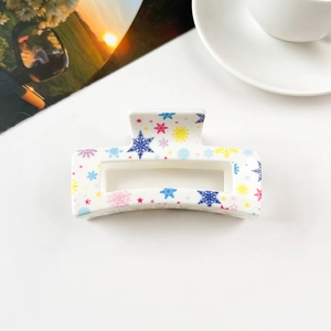 Detailed view of square hair claw clip with colorful snowflake patterns on a desk