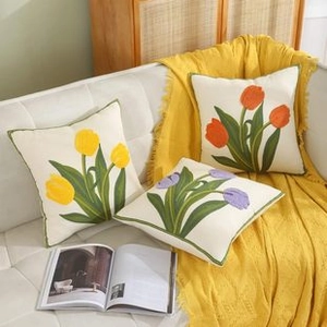 Detailed embroidery of colorful tulips on cream cushion covers with green piping edge