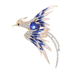 Elegant gold phoenix brooch with blue enamel wings and sparkling rhinestones on white background