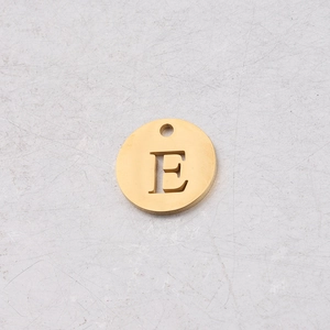 Vue macro d'un pendentif rond 12mm en acier doré avec découpe de la lettre majuscule E