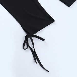 Detailed view of the black lace jumpsuit featuring lace-up tie cuffs and knit fabric texture