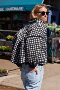 Street style shot of a black and white checkered quilted jacket with stand collar detail