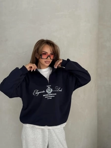 Detail of navy blue half-zip sweatshirt featuring white text print and high collar