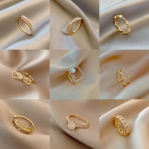 Detailed grid of adjustable gold rings with pearls and zircons on elegant silk