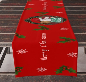 Detail of red linen Christmas table runner with Santa motifs on rustic dark wood surface