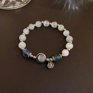 Macro detail of cat eye beads and vintage silver pendant on beaded elastic bracelet