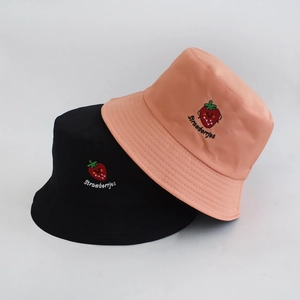 Detail view of double-sided bucket hats in black and pink with strawberry embroidery