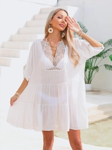 Detailed close-up of white crochet lace neckline and textured fabric beach cover-up