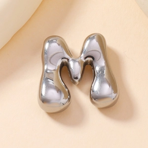Macro shot of silver bubble letter M pendant with high-shine metallic finish