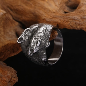 Detailed shot of retro silver double wolf head relief ring on rustic dark wood base