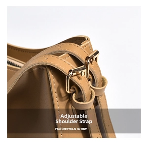 Detail view of adjustable leather shoulder strap with golden buckle on brown tote bag