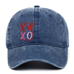 Detail of red XOXO heart embroidery on a vintage washed navy blue denim baseball cap