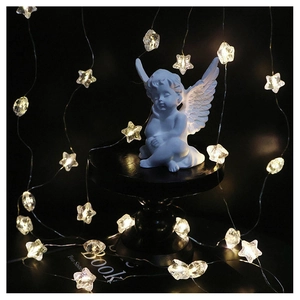 Close-up of a white Cupid angel figurine with warm star-shaped LED string lights