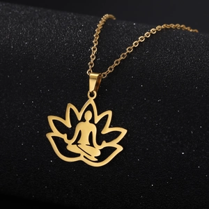 Macro detail of golden lotus flower pendant with meditation figure on dark background