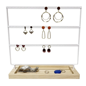 Close-up of white 3-tier jewelry stand with metal earring holes and wooden base tray