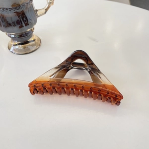Detail of amber tortoiseshell hair claw clip with gradient texture and metal spring