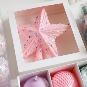 Pink glittery Christmas tree star topper with colorful sprinkles in a white gift box