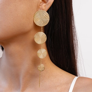 Close-up of long gold geometric fringe earrings with textured metal discs on a model