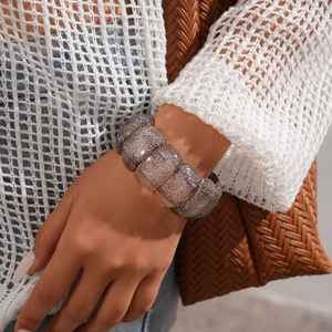 Close-up of brown glitter acrylic wide bangle bracelet worn with knitwear