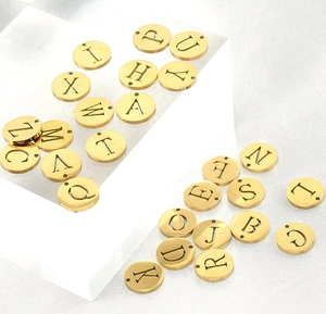Close-up of golden stainless steel round alphabet pendants with hollowed letter designs