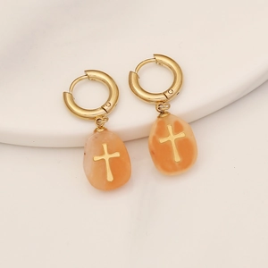 Detailed view of gold cross drop earrings with orange teardrop stone charms