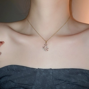 Detail of 18k gold plated flower necklace and crystal pendant worn on the neck