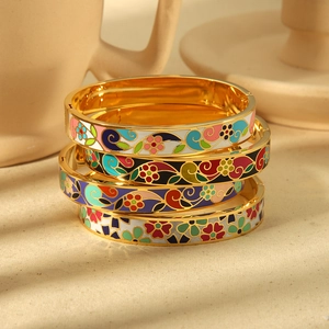 Lot de quatre bracelets joncs en acier titane avec fleurs en émail et finitions dorées