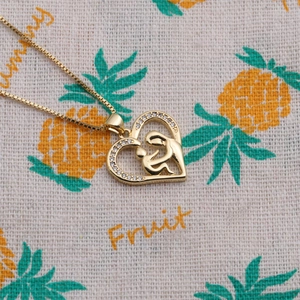 Gros plan du collier en cœur doré avec pendentif de maternité et oxydes de zirconium