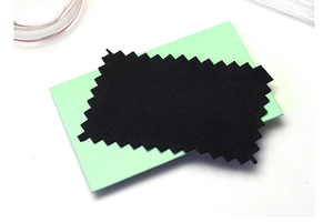 Macro detail of black microfiber cleaning cloth on a mint green jewelry gift box