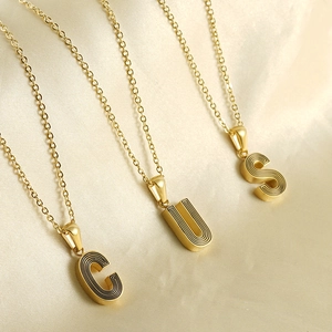 Gros plan détaillé des pendentifs alphabet plaqués or 18k avec fine texture circulaire