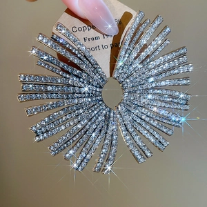 Macro shot of silver fan-shaped earrings with rhinestones held in hand with sparkles