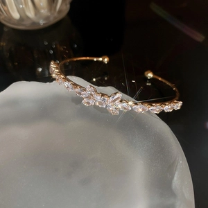 Macro shot of gold bow cuff bracelet with sparkling zircon stones on dark backdrop