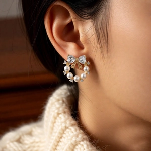 Detail of bow-knot pearl earrings with crystals shown on a model for a realistic look
