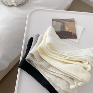 Close-up of mesh knit socks with ruffle cuffs in neutral tones on a tray