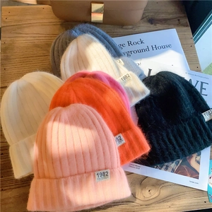 Detail view of colorful knitted beanies stacked with 1982 California woven labels