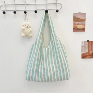 Detailed view of a blue and white striped canvas tote bag hanging on a minimalist wall hook