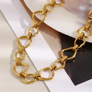 Detailed view of 18K gold plated stainless steel heart chain necklace on a shell