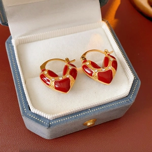Detail of red enamel heart earrings with gold plating and rhinestones in a blue jewelry box