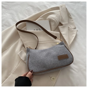 Detail of grey tweed shoulder bag with brown leather trim and metallic gold hardware