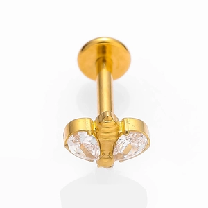 Macro d'un piercing en titane G23 doré avec deux zircons en goutte et base plate lisse
