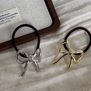 Detailed close-up of metallic bow hair ties in gold and silver finish with elastic band